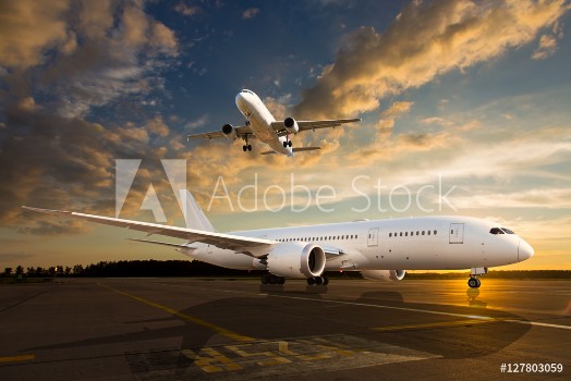 Picture of White passenger airplane on airport runway during sunset And aircraft in the sky